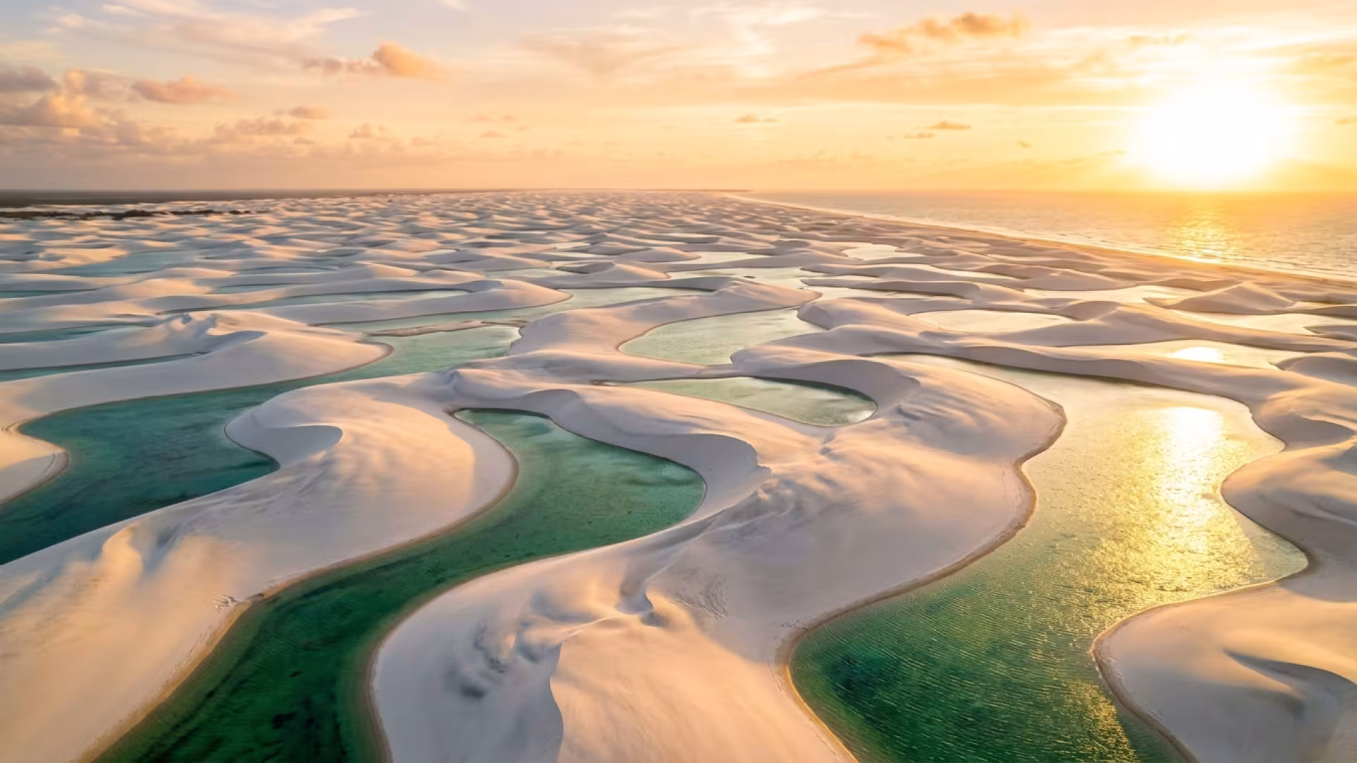 Dunas brancas e lagoas de água doce cristalina nos Lençóis Maranhenses ao pôr do sol